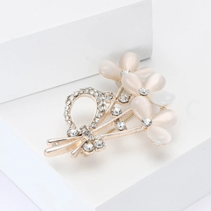 Broche bouquet floral doré avec pétales en opale et ruban en cristal sur bloc blanc