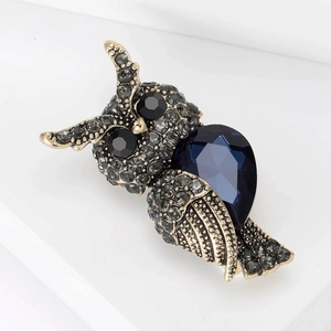 Detail of vintage owl brooch with blue teardrop crystal and grey rhinestones in gold