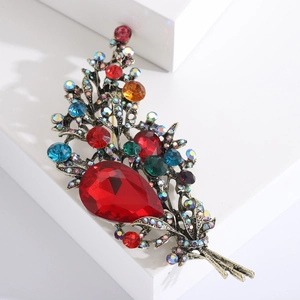 Macro detail of vintage floral brooch featuring red teardrop crystals and antique gold finish