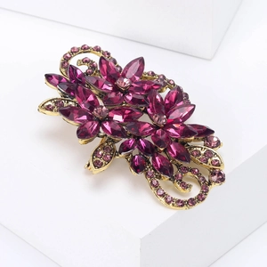 Macro detail of vintage floral brooch with purple crystal petals on gold metal base