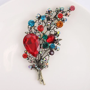 Detail of vintage flower bouquet brooch with multicolored crystals on a white ceramic plate