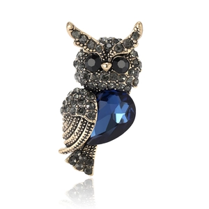 Vintage gold owl brooch with dark blue teardrop crystal and grey rhinestones on white
