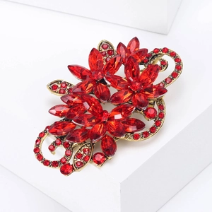 Macro detail of retro gold flower brooch with red crystal petals and sparkling gems