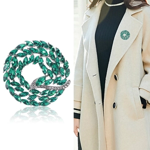 Elegant crystal wreath brooch with green marquise stones and white rhinestones on coat