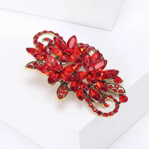 Detail of vintage flower brooch with vibrant red crystals and golden alloy vine base