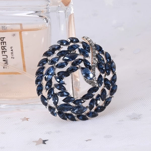 Elegant spiral circular brooch with navy blue marquise crystals and sparkling white diamonds