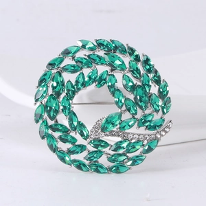 Detail of a silver floral brooch with marquise emerald green stones and pavé crystals