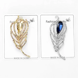Detailed macro view of feather brooches with teardrop gemstones and micro-pave crystals