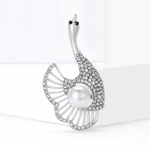 Élégante broche cygne argentée avec cristaux et perle sur un socle blanc pur