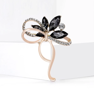 Broche nœud élégante ornée de cristaux noirs et de strass sur une base dorée