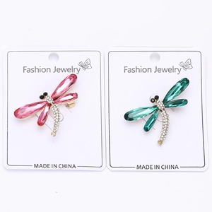 Detailed close-up of pink and green dragonfly brooches with crystal wings on gold alloy