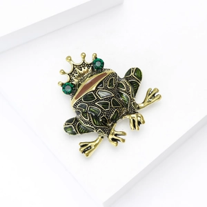 Vintage green enamel frog prince brooch with gold crown and crystal eyes on white pedestal