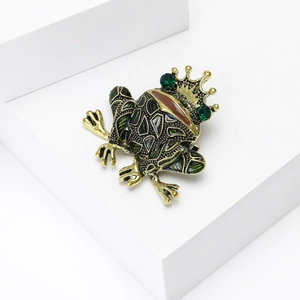 Vintage enamel frog prince brooch with crown and green crystals on a clean background