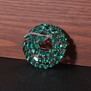 Macro shot of green marquise-cut crystal wreath brooch with silver micro-pave detailing