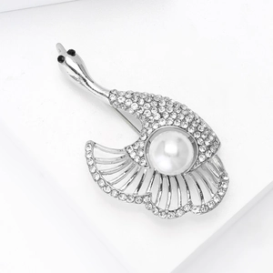 Détail d'une broche cygne argentée ornée de cristaux et d'une perle blanche