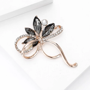 Détail d'une broche fleur or rose avec cristaux gris foncé et strass étincelants