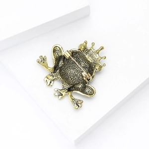 Close-up of vintage gold frog brooch back showing metal texture and safety pin clasp