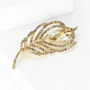 Macro shot of gold feather brooch with rainbow crystals and champagne teardrop stone