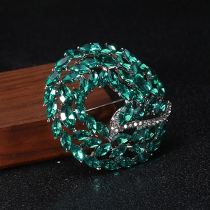 Detailed view of emerald marquise-cut crystal circle brooch with sparkling white rhinestones