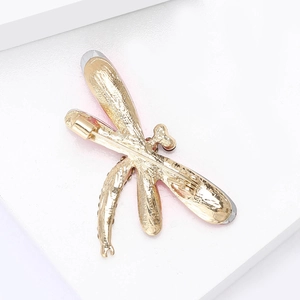 Detailed back view of a gold dragonfly brooch showing the safety pin and red enamel wings
