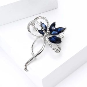 Vue détaillée d'une broche fleur argentée avec gemmes bleu foncé sur un support blanc