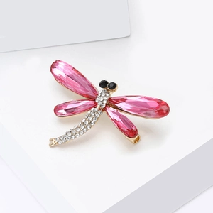 Macro shot of a dragonfly brooch featuring pink crystals and white rhinestones on a gold base