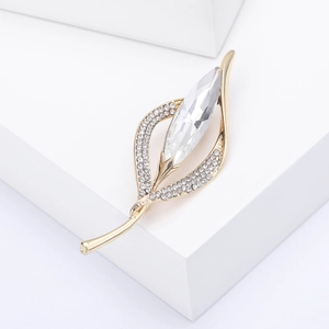 Vue détaillée d'une broche feuille dorée avec un grand cristal marquise et des diamants