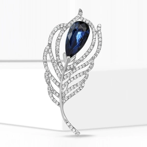 Elegant silver feather brooch with sparkling diamonds and a pear-cut blue crystal gemstone