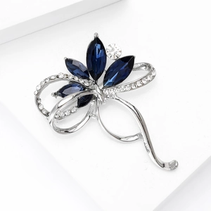 Gros plan d'une élégante broche argentée avec cristal bleu et strass scintillants