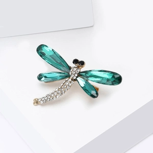 Detailed macro view of an emerald green dragonfly brooch with crystal wings and rhinestones