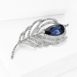 Macro shot of silver feather brooch with white rhinestones and a blue teardrop stone