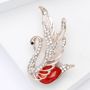 Elegant swan brooch with white rhinestones and a large red heart crystal on gold base