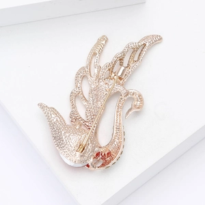 Detailed back view of a golden swan brooch showing the safety pin clasp and gems