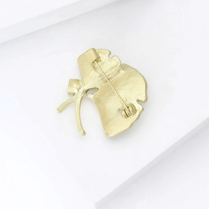 Vue arrière détaillée d'une broche en feuille de ginkgo avec fermoir et texture métallique