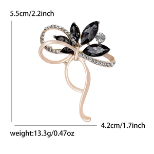 Élégante broche nœud en or rose avec cristaux noirs et diamants sur fond blanc