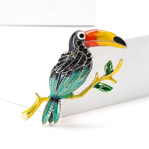 Broche toucan en émail exquise avec strass bleus et branche dorée sur présentoir blanc
