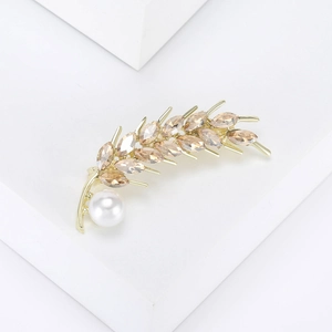 Détail d'une broche épi dorée ornée de cristaux champagne et d'une perle ronde