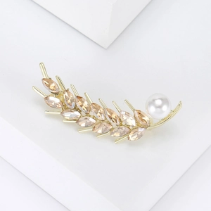 Macro detail of golden wheat ear brooch featuring amber crystals and a large white pearl