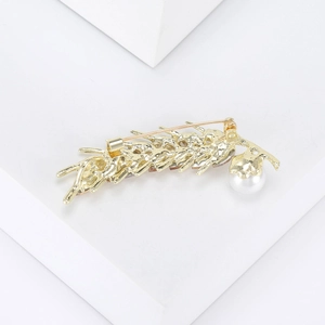 Detailed macro view of the gold wheat brooch back with secure pin and white pearl