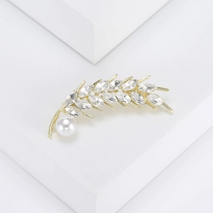 Detailed macro view of wheat ear brooch with sparkling crystals and a white pearl