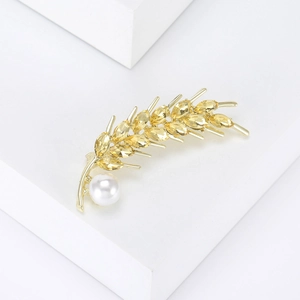 Detail of wheat ear brooch with yellow crystals and a white pearl on white display stand