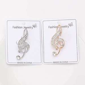 Macro shot of silver and gold musical treble clef brooches with sparkling crystals