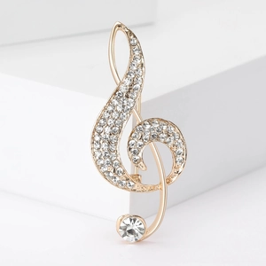 Elegant gold-tone musical note brooch with sparkling rhinestones on a white stand