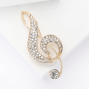 Detail of a golden treble clef brooch with shimmering rhinestones on a white background