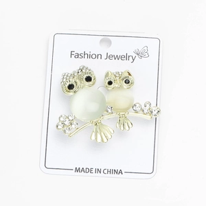 Detail view of owl brooches with white opal stones and sparkling crystal accents