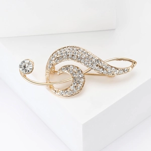 Detailed view of music note brooch with gold plating and sparkling white rhinestones