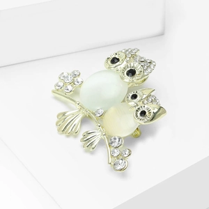 Close-up of golden owl family brooch with opal stones and sparkling rhinestone details