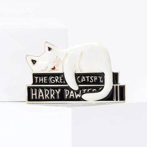 Creative enamel cat brooch featuring white cat on books with Great Catsby gold lettering