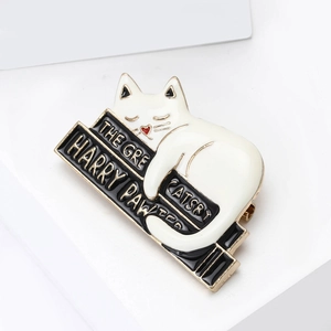 Detail of cute cat on books enamel pin with Harry Pawter gold plating text