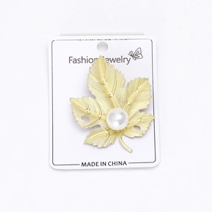 Détails de la texture et de l'incrustation de perles de la broche feuille dorée